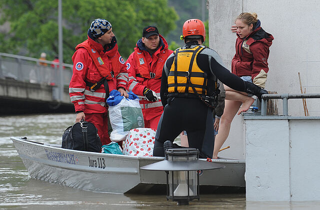 Hochwasser: Frauen werden von Helfern der DRK - Wasserwacht mit dem Boot aus ihrer Wohnung gerettet.